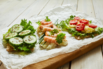 Slices of waffle bread with different vegetables, shrimp and seasoning
