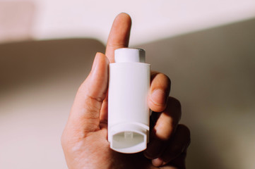A young person is holding an asthma inhaler device