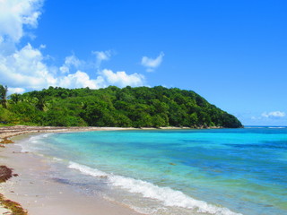 Fototapeta na wymiar la mer turquoise et une colline entour une plage déserte