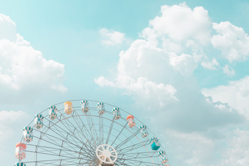 Retro pastel colorful ferris wheel of the amusement park in the blue sky  and cloud background.
