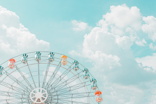 Retro pastel colorful ferris wheel of the amusement park in the blue sky  and cloud background.