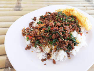 Stir fried basil with minced meat. Served with fried egg and on top of rice. Popular Thai street food. Top view on table.