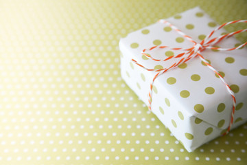 Green gift with ribbon on the green polka dot background