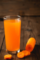 Carrot juice in glass on wooden table.