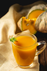 Fresh pumpkin juice in glass on wooden table.