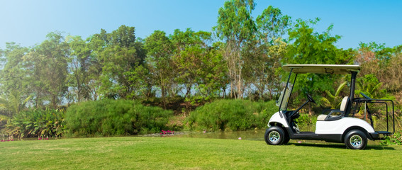 Golf cart car in fairway of golf course with fresh green grass field and cloud sky and tree,panorama - 296459449