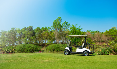 Golf cart car in fairway of golf course with fresh green grass field and cloud sky and tree - 296459481