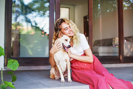 Beautiful Caucasian Woman Hugging Her Mongrel Dog Pet In Front Of Her House