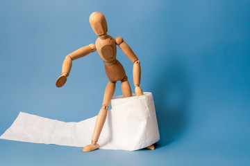 Wooden figure sit on a roll of toilet paper. Concept of the problem with digestion.