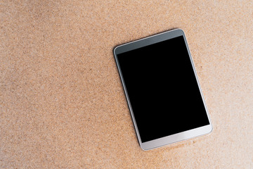 Fototapeta premium Smart phone on sand beach texture background.