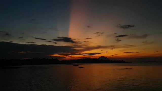 Slow motion panning video of a beautiful sunset with a volcano in the background