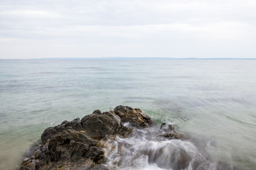 Fototapeta na wymiar Felsen im Meer wird vom Wasser umspült