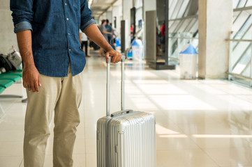 A male traveler wearing a gray hat Preparing to travel He has a trolley bag He stands at a large...