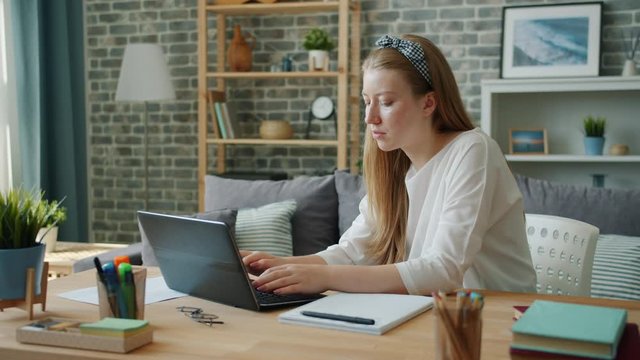 Female student pretty young woman is studying at home using laptop typing then writing in notebook. Education, people and modern lifestyle concept.