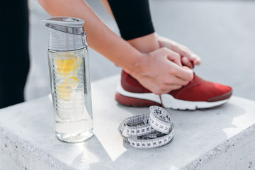 Closeup glass bottle of water with lemon and tape measure