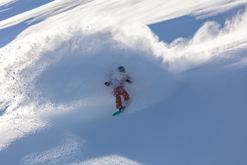 Freeride snowboarder girl riding off-trail fresh powder snow high in the mountains. Unrecognizable woman heliski snowboarding untouched terrain in snowy mountains. Heliboarding remote pristine slopes