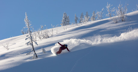Extreme snowboarder has fun riding fresh powder snow off piste in white mountains. Pro rider...