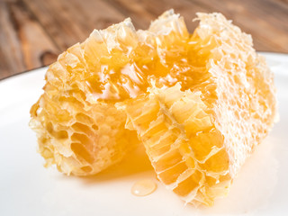 Top view of the wooden spoon of bee pollen with honeycombs on wooden background. Selective focus