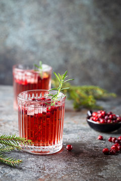 Fresh cranberry cocktail with rosemary in a glass on gray background.