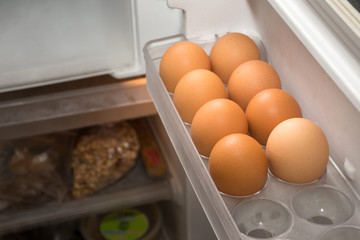 Chicken eggs on the refrigerator shelf.