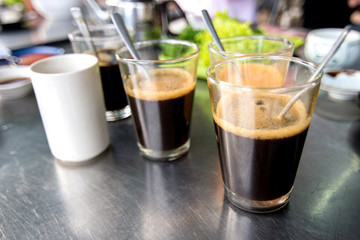 Black coffee in transparent glass on stainless table in breakfast restaurant.