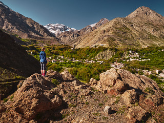 Hiker blonde girl standing over green mountain valley of Imlil in High Atlas