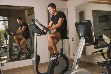 An athlete is engaged in the gym, a Young man does cardio on an exercise bike