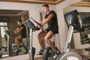 Fototapeta premium An athlete is engaged in the gym, a Young man does cardio on an exercise bike