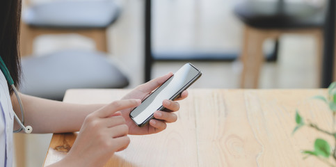 Close-up view of young professional female doctor holding blank screen smartphone