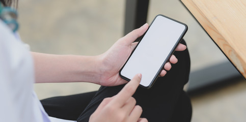 Close-up view of young female doctor touching blank screen smartphone