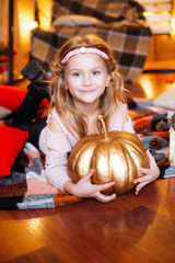 Cute girl of school age with blond  hair in an autumn studio with yellow leaves, plaids, pumpkins and apples