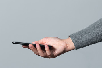 Mobile phone in female hand isolated on gray background.