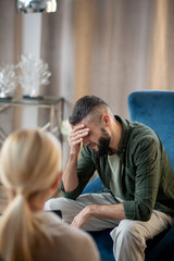 Dark-haired man talking about depression to psychologist