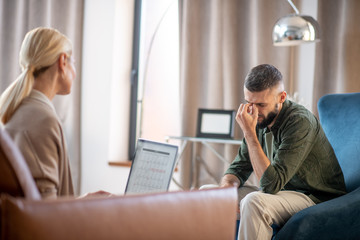 Dark-haired man feeling concerned while visiting psychoanalyst