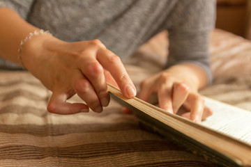 Young woman having rheumatoid is reading a book. Hands and legs are deformed. She feels pain. Selective focus.