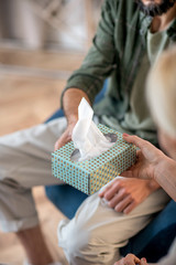 Close up of psychoanalyst giving pack of napkins to patient