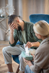Man having some tears while sharing problems with psychoanalyst