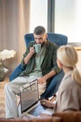 Blonde psychoanalyst holding laptop and speaking with patient