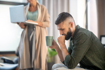 Bearded man drinking tea and speaking with psychoanalyst