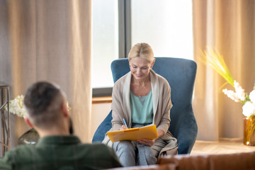Psychoanalyst smiling while making notes and talking to patient