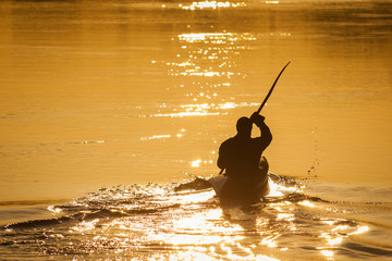 Paddler on river in golden sunlight