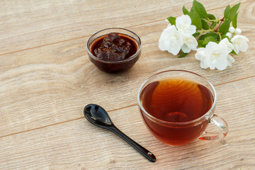 Glass cup of tea, strawberry jam with white jasmine flowers.