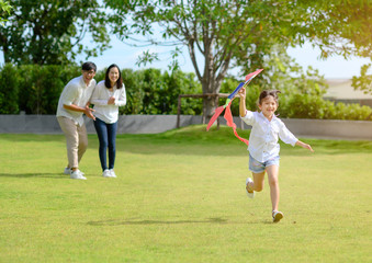 Fototapeta premium a little girl daughter run o family with holding kite in hand t in field park of village
