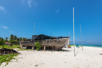 Fototapeta na wymiar An old wooden fishing boat on the coast of the Maafushi Island, Maldives. Paradise tropical island. Local life. Travel and tourism concept.