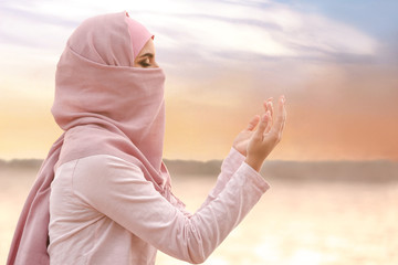 Naklejka na ściany i meble Beautiful Muslim woman praying outdoors
