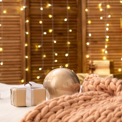Obraz na płótnie Canvas the bedroom is decorated for Christmas. the bed is covered with a soft design Merino large knitted blanket. the walls are decorated with lights of garlands.cozy gentle atmosphere of the Lodge of love