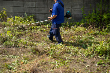 草刈機で草を刈る作業員の男性