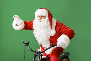 Santa Claus riding bicycle on color background