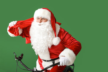 Santa Claus with bag riding bicycle on color background