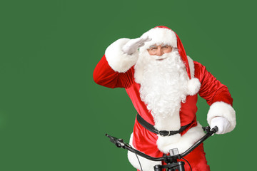 Santa Claus with bicycle looking far away on color background